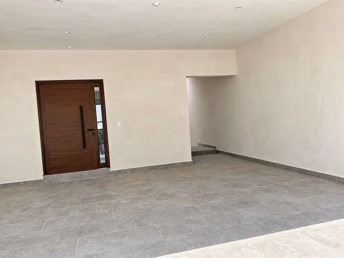 Vestíbulo de acceso con puerta pivotante de madera
